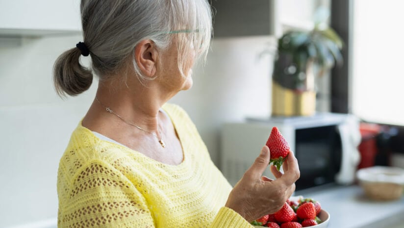 Older woman holding a bowl of strawberries