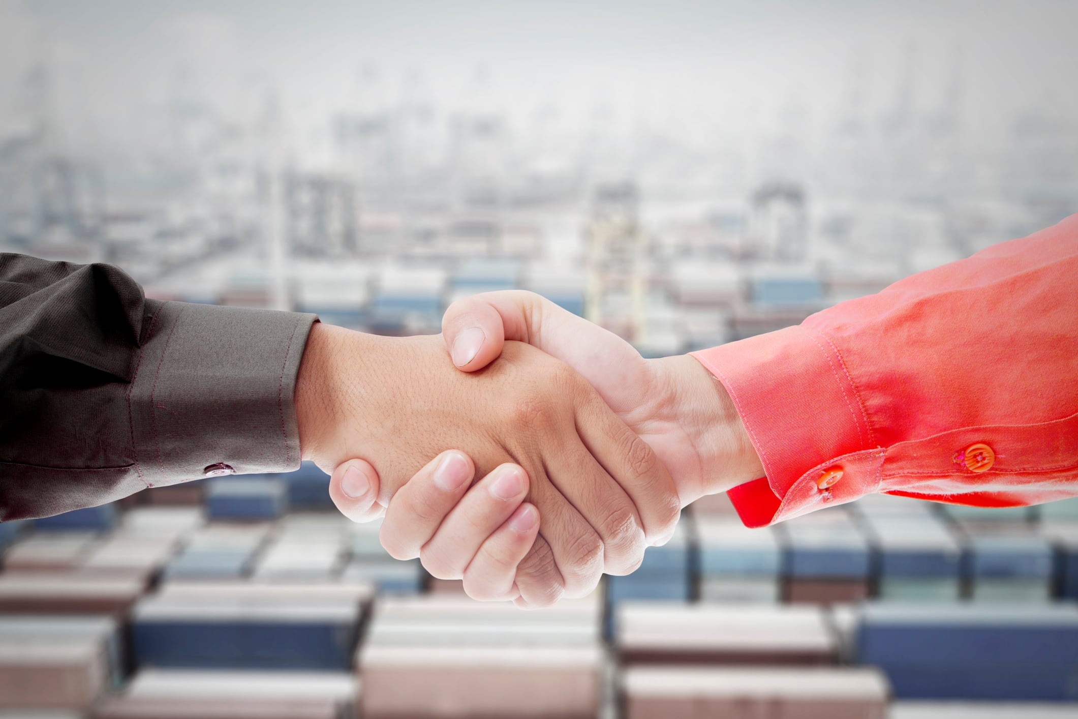 Business Handshake Over Shipping Containers Symbolizing Trade Agreement and Partnership