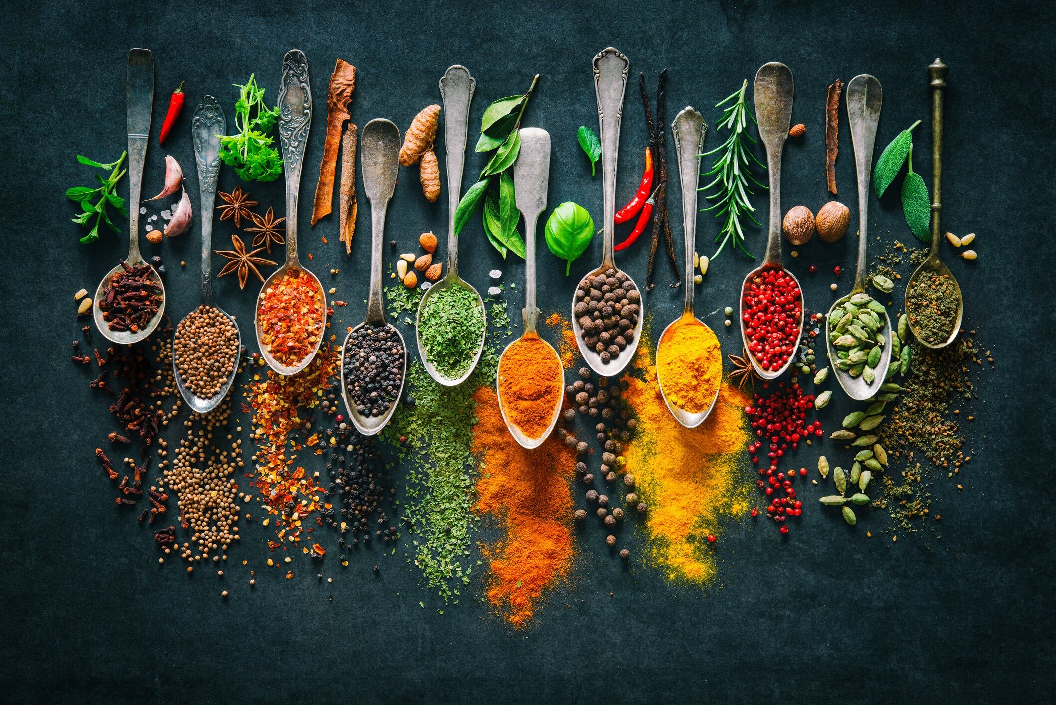 Colourful various herbs and spices for cooking on dark background.