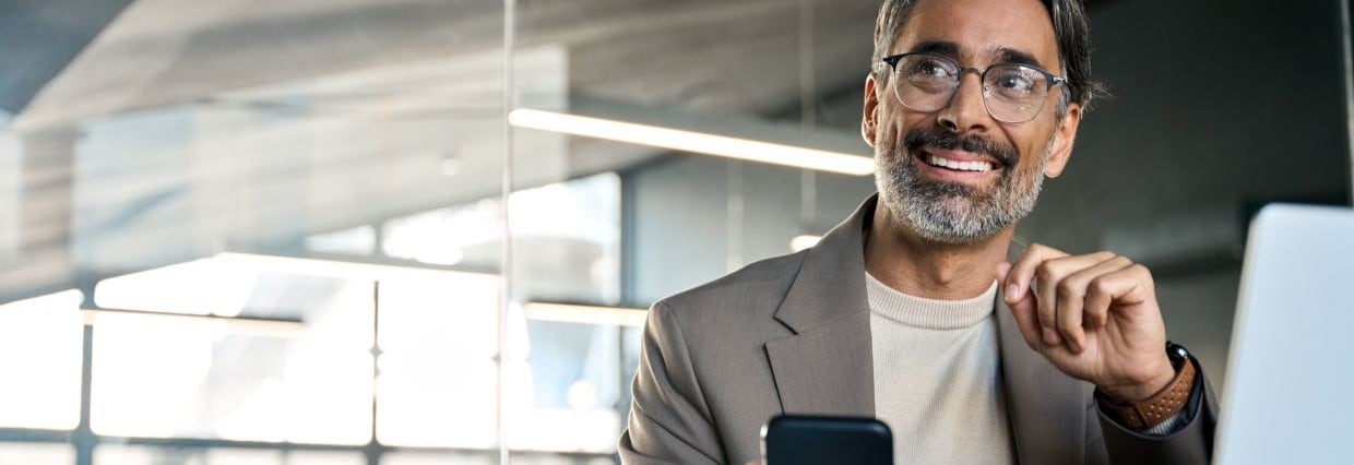 Man smiling in office with phone