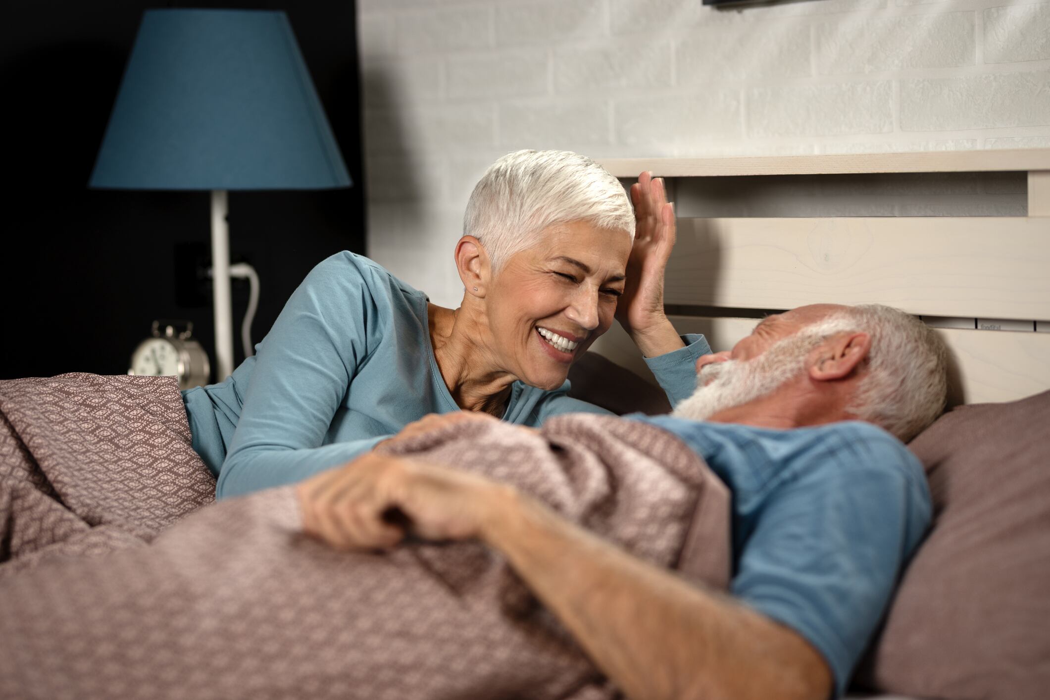Love lives forever! Senior couple at home. Handsome old man and attractive old woman are enjoying spending time together while lying in bed.