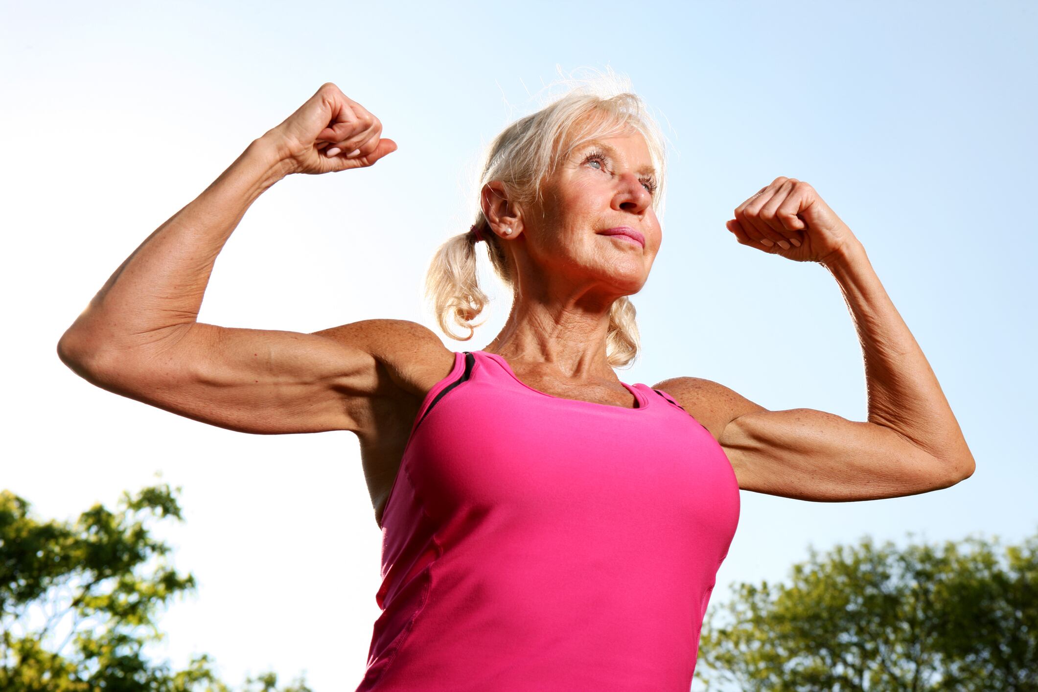 Older woman flexes her bicep muscles along the Chicago, IL, lakefront.