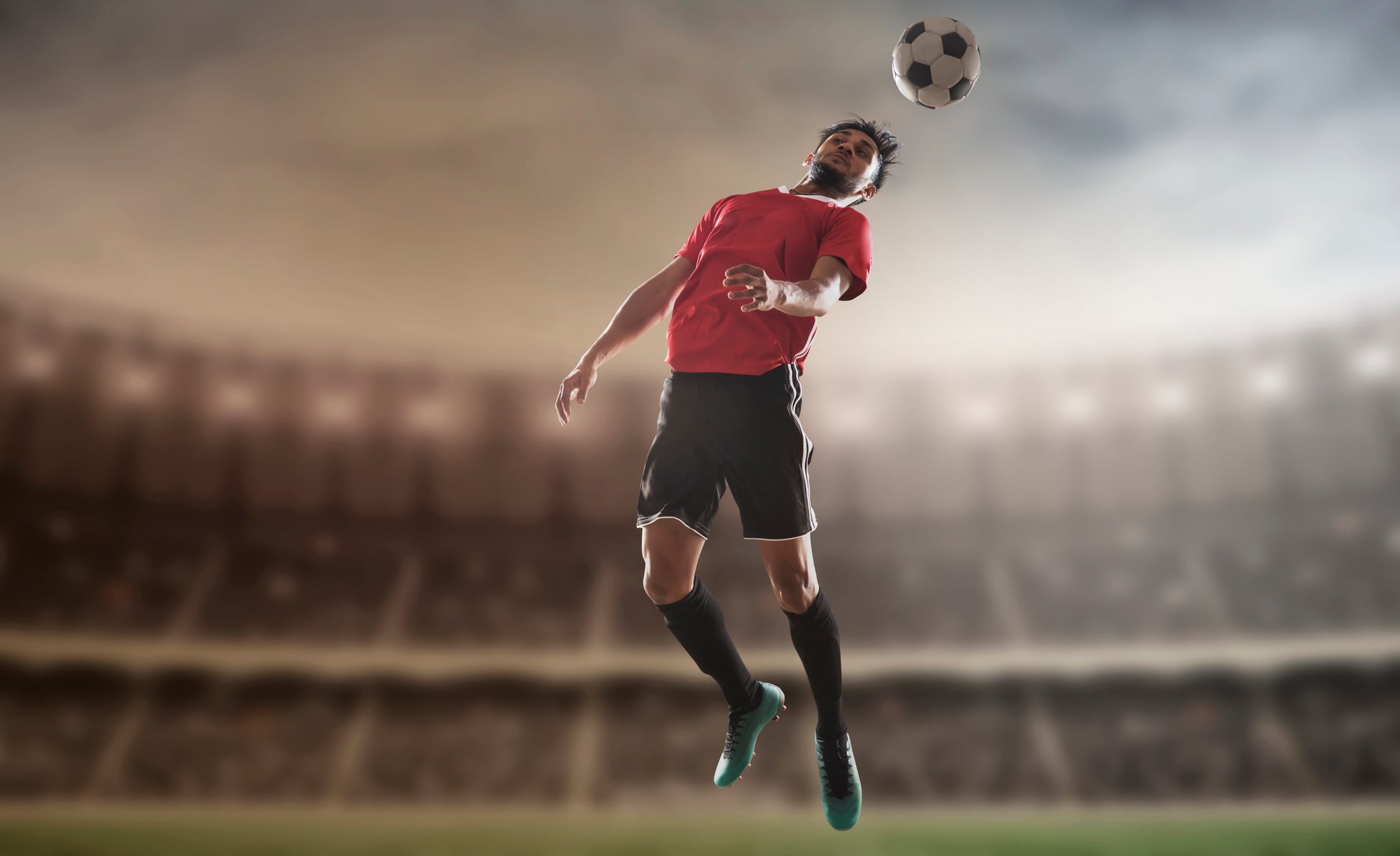 Footballer heading football in stadium