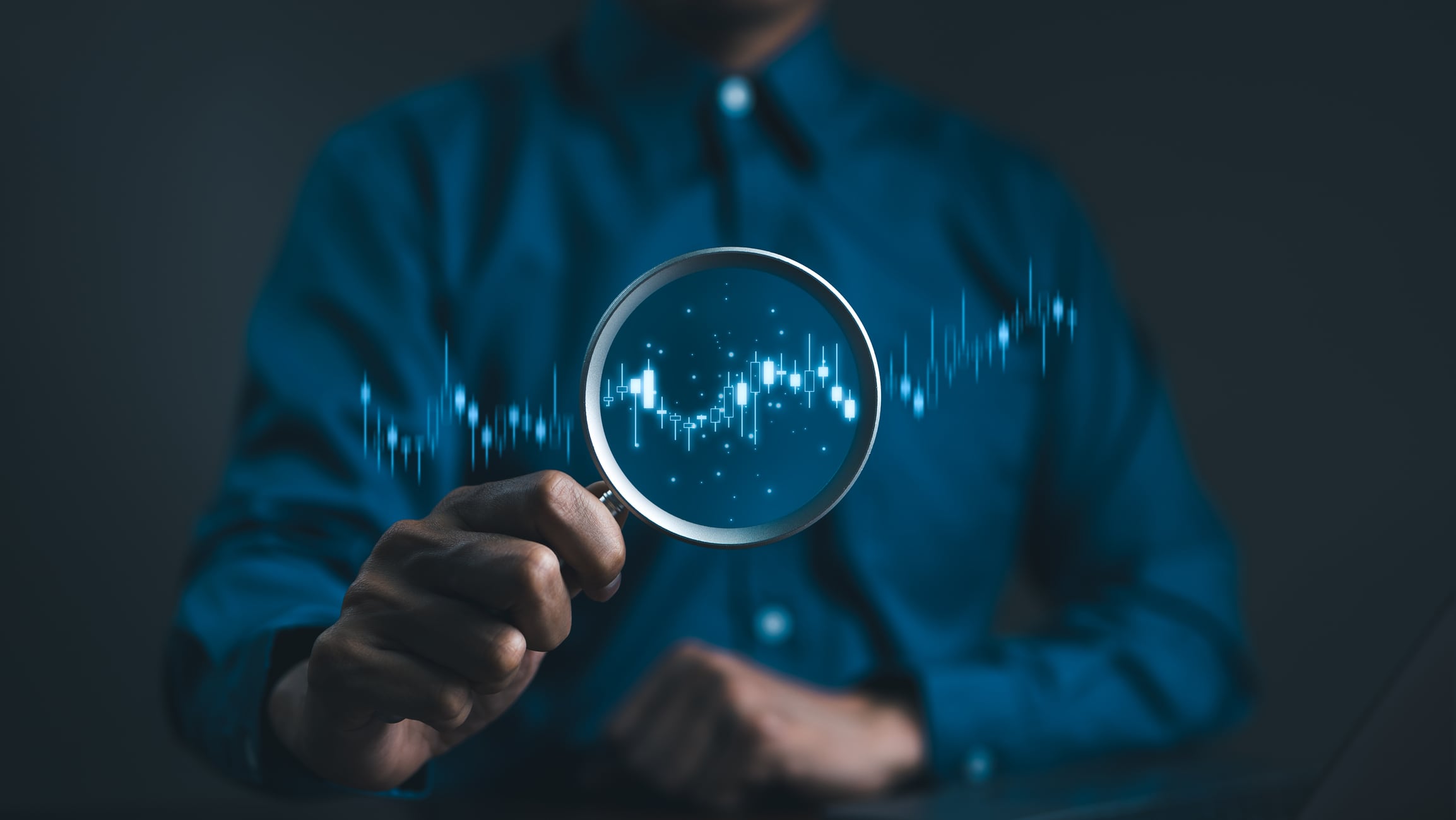Stock trading and investing concept. Businessman or trader hand holding magnifying glass with virtual stock graph market chart. foreign exchange, trade fund, crypto money, Business growth, investor,