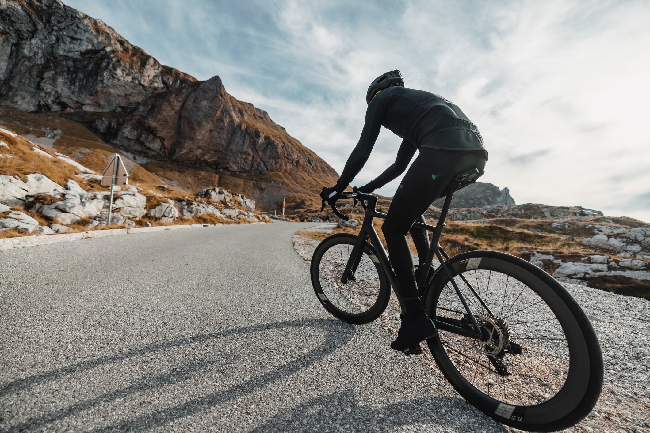 A recreational male cyclist on a mountainous road, wearing his cycling gear, helmet, and gloves. The focus is on his muscular build and his love for cycling and keeping fit.