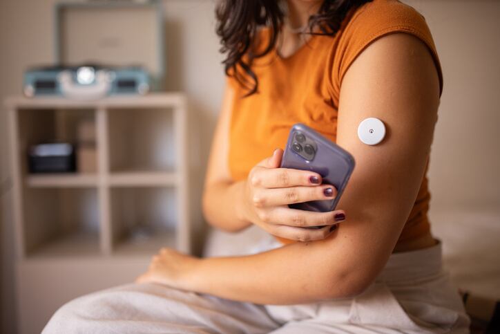 Young diabetic patient monitoring glucose level with remote sensor at home, she has a glucose monitor on her arm.