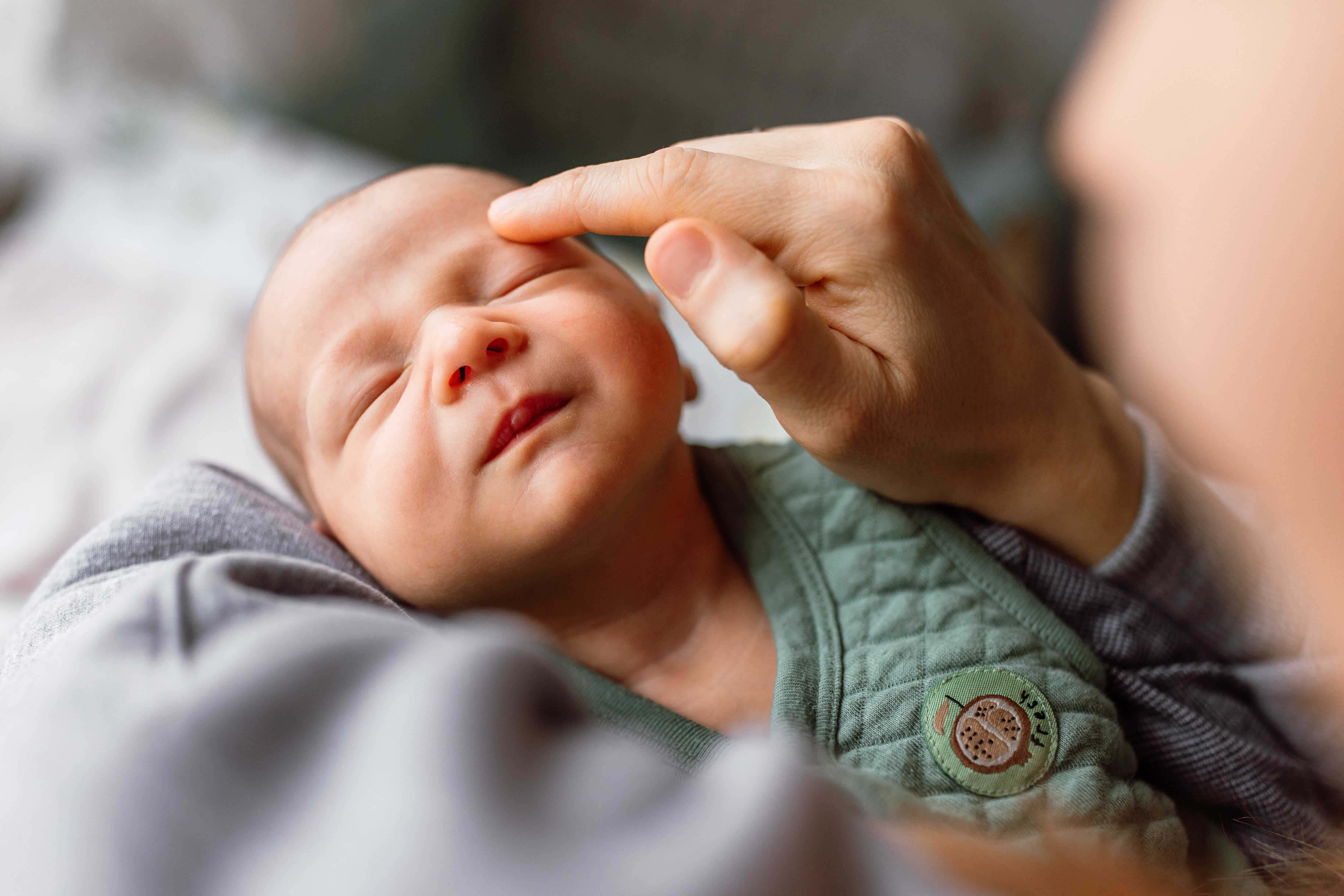 Mother holding baby boy, tracing a finger over his face