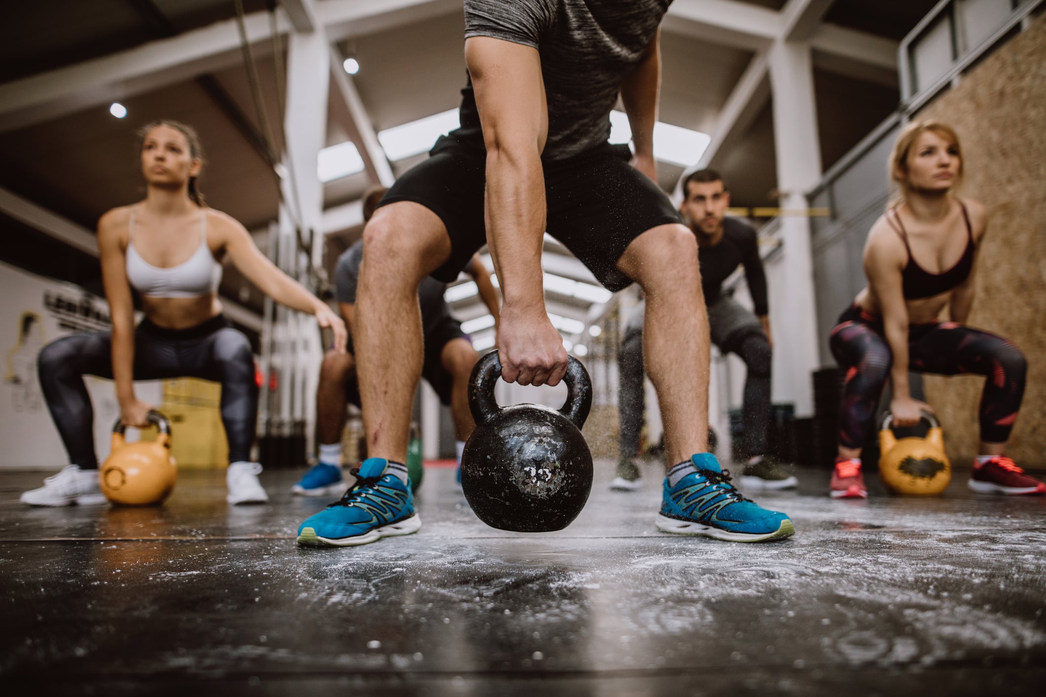 CrossFit workout: Group of men and women squatting with kettlebells