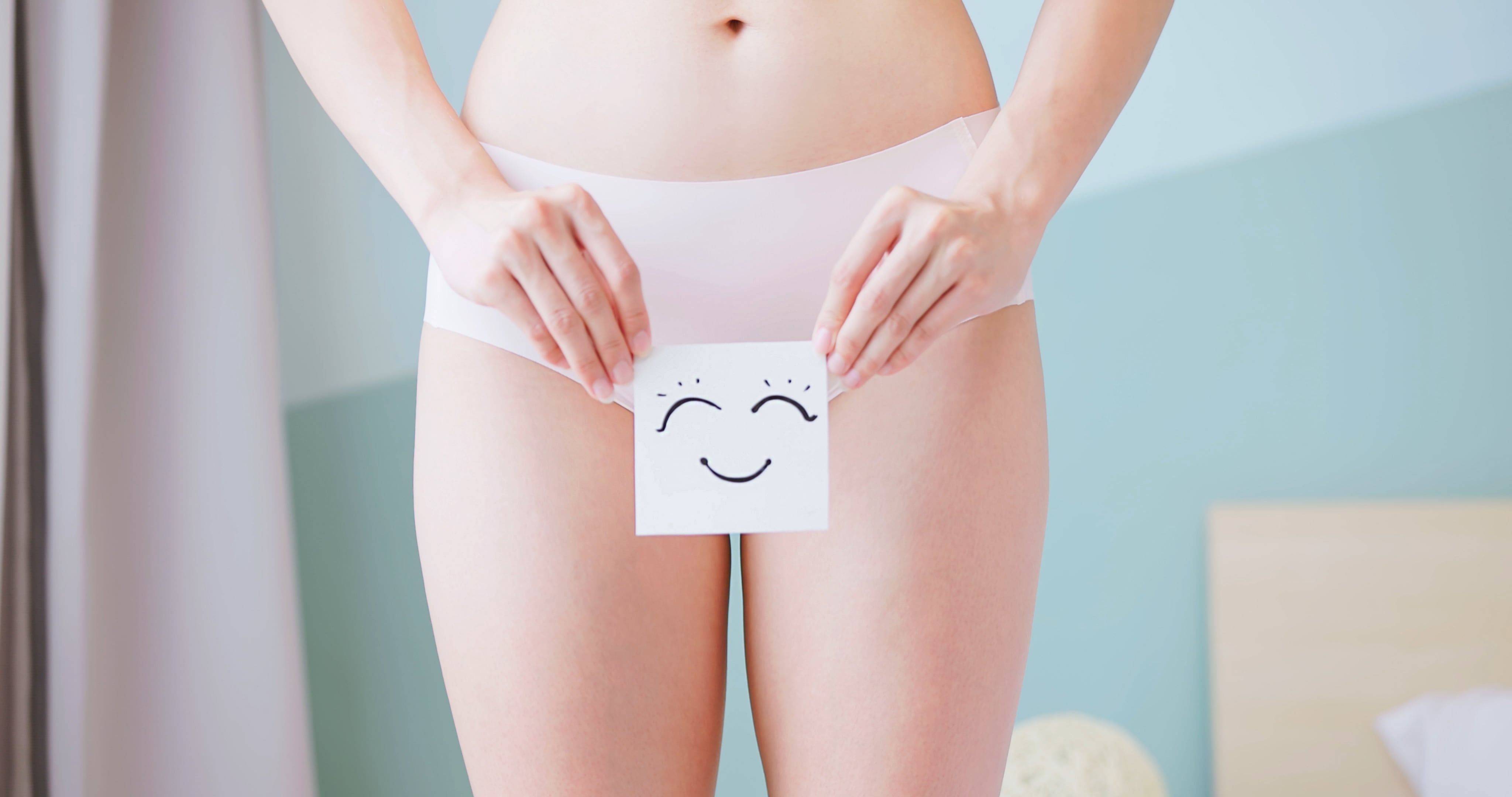 woman holds smiley face in front of body