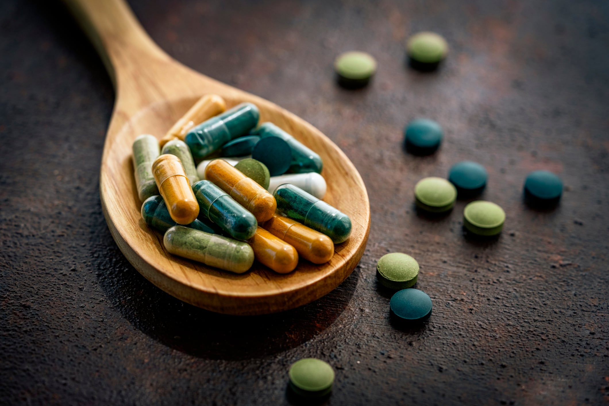 Alternative medicine: Close up of mutritional supplement capsules and pills in a wooden spoon