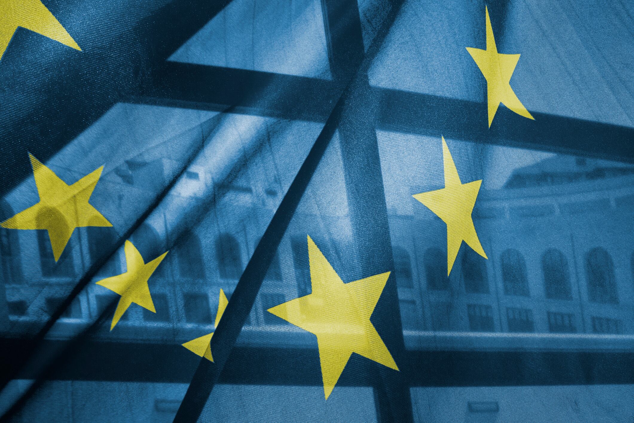 Classical building appears through a EU flag.