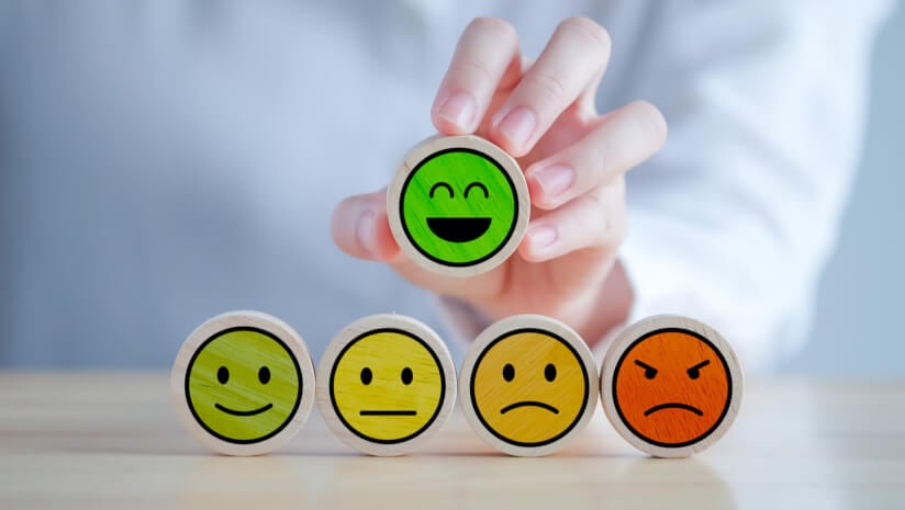 Hand holds up a smiley face among range of potential survey responses