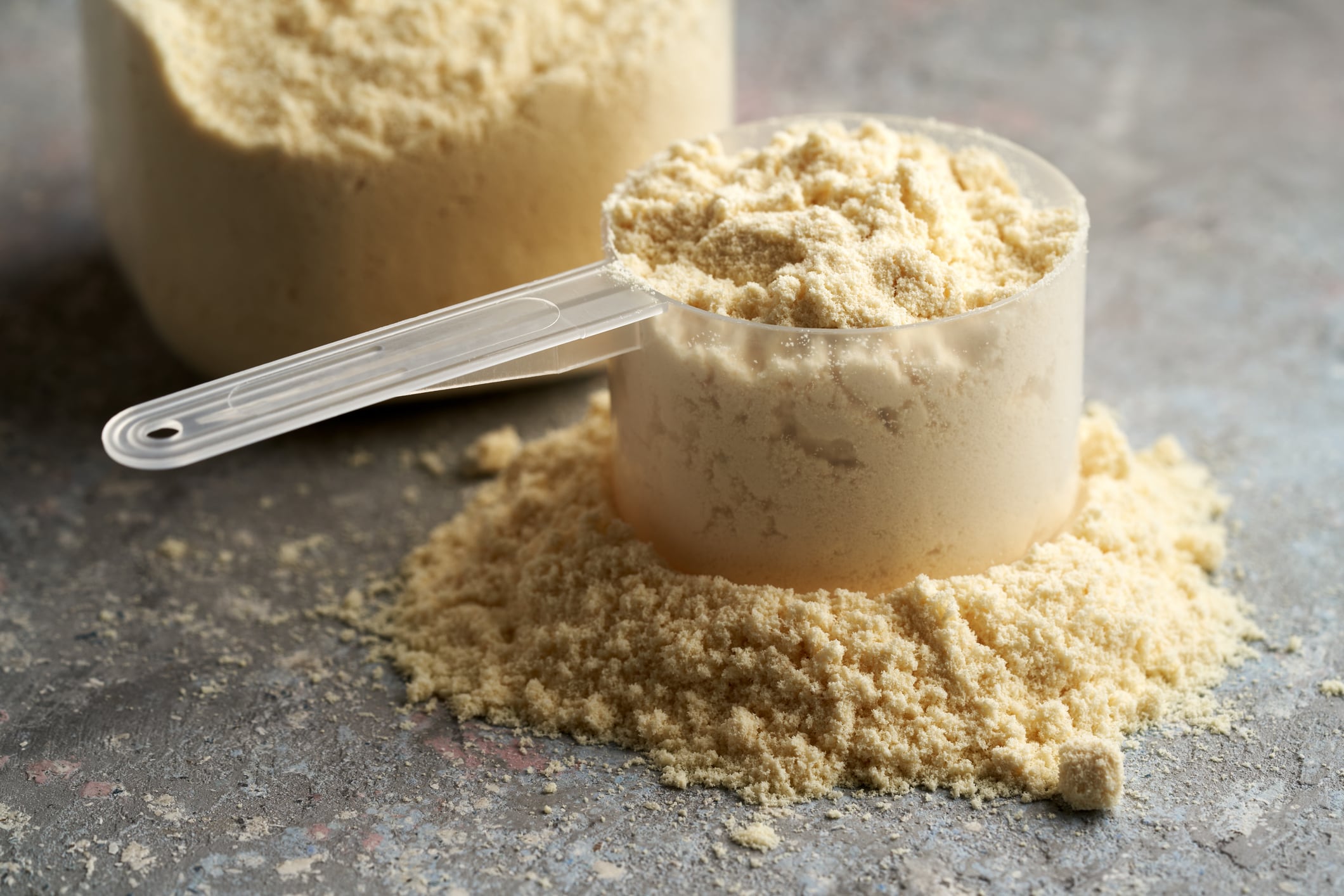 Vanilla flavoured whey protein powder in a plastic measuring scoop