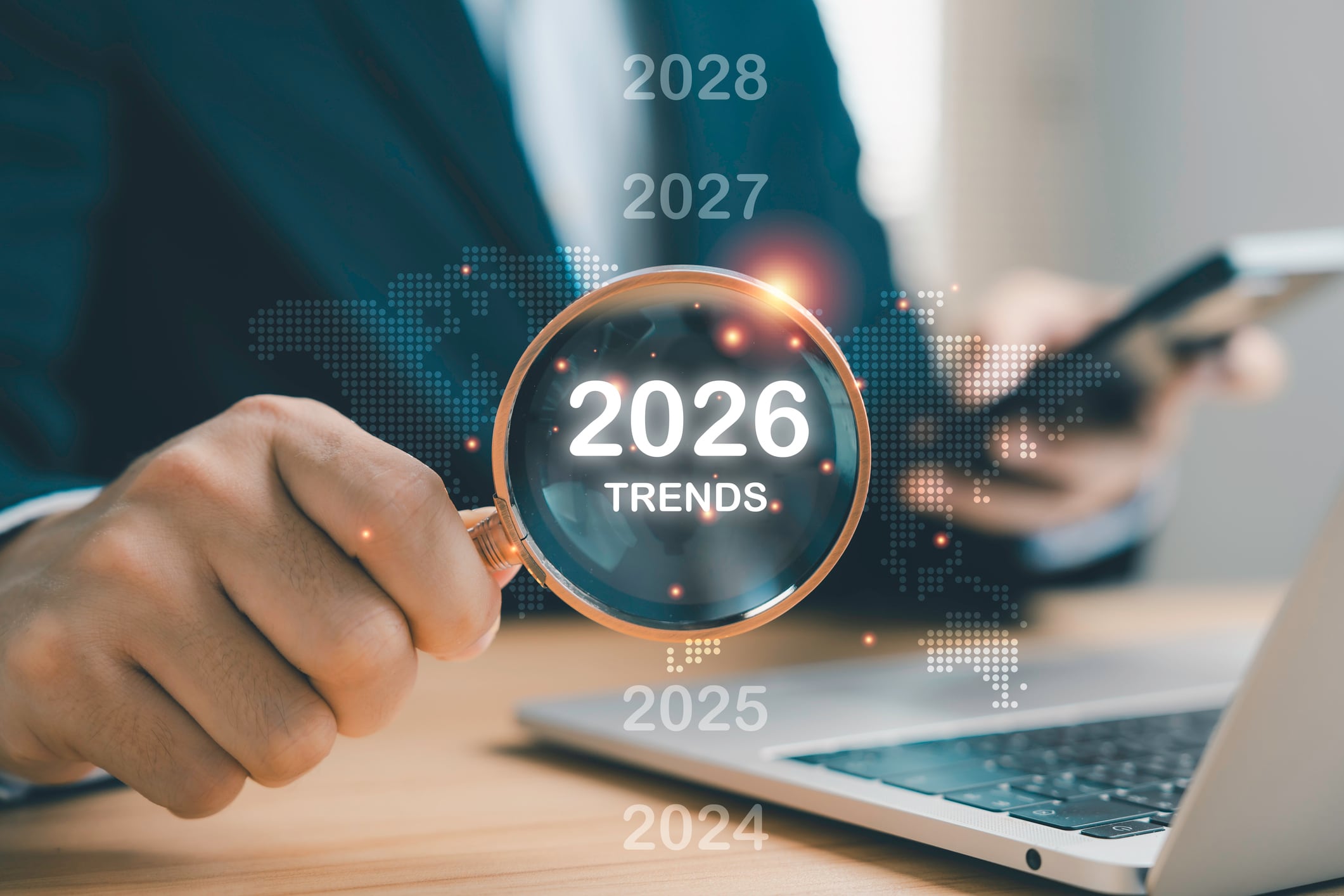 Businessman holding magnifying glass with 2026 trends text, future business innovation and market forecast concept for strategic planning, growth opportunities, and digital transformation.