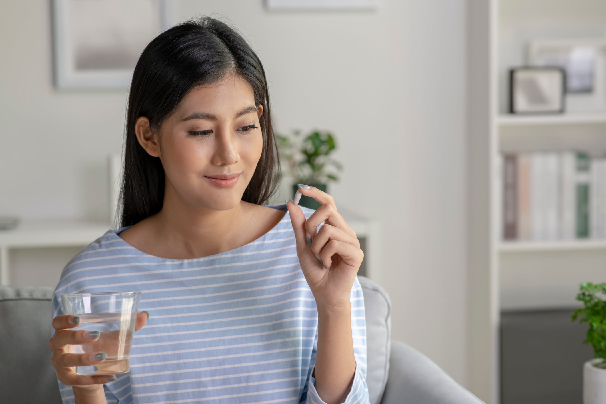 Young Asian woman taking pill and vitamin in the living room.