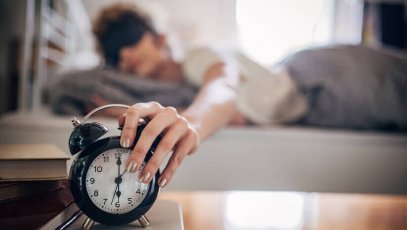 Woman reaching to turn off the alarm clock