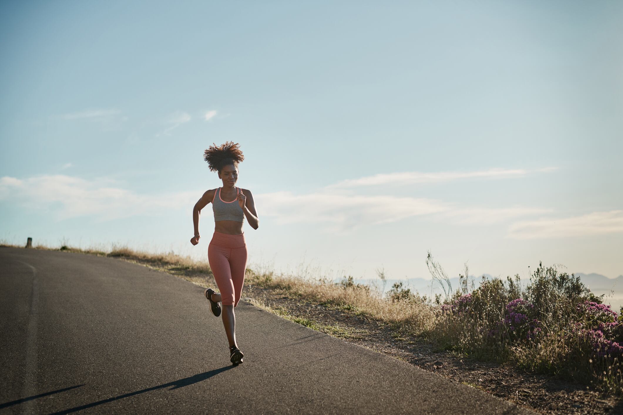 Shot of a young woman in full stride running on a scenic route