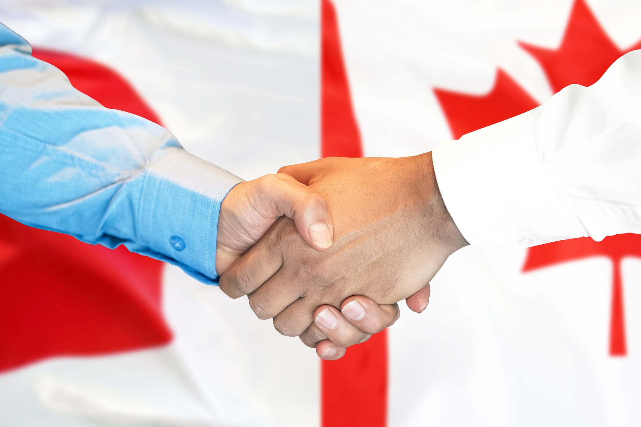 Business handshake on the background of two flags. Men handshake on the background of the Canada and Japan flag. Support concept