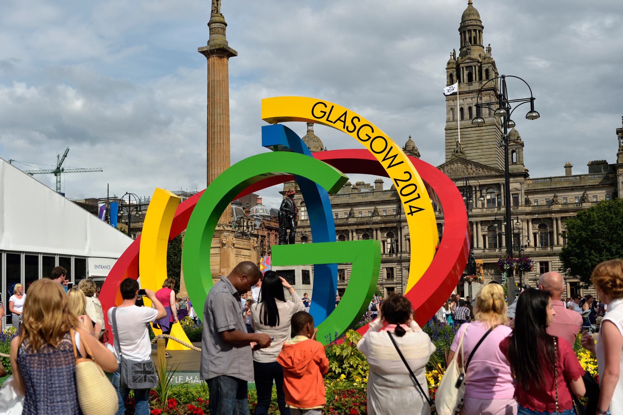 Glasgow, Scotland - August 1, 2014: Members of the public in George Square, standing beside the logo for the 2014 Commonwealth Games which is being held in Glasgow, Scotland.