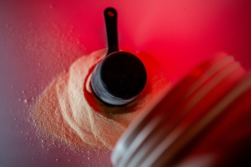 Pre-workout: black scoop and powder against a red backdrop.
