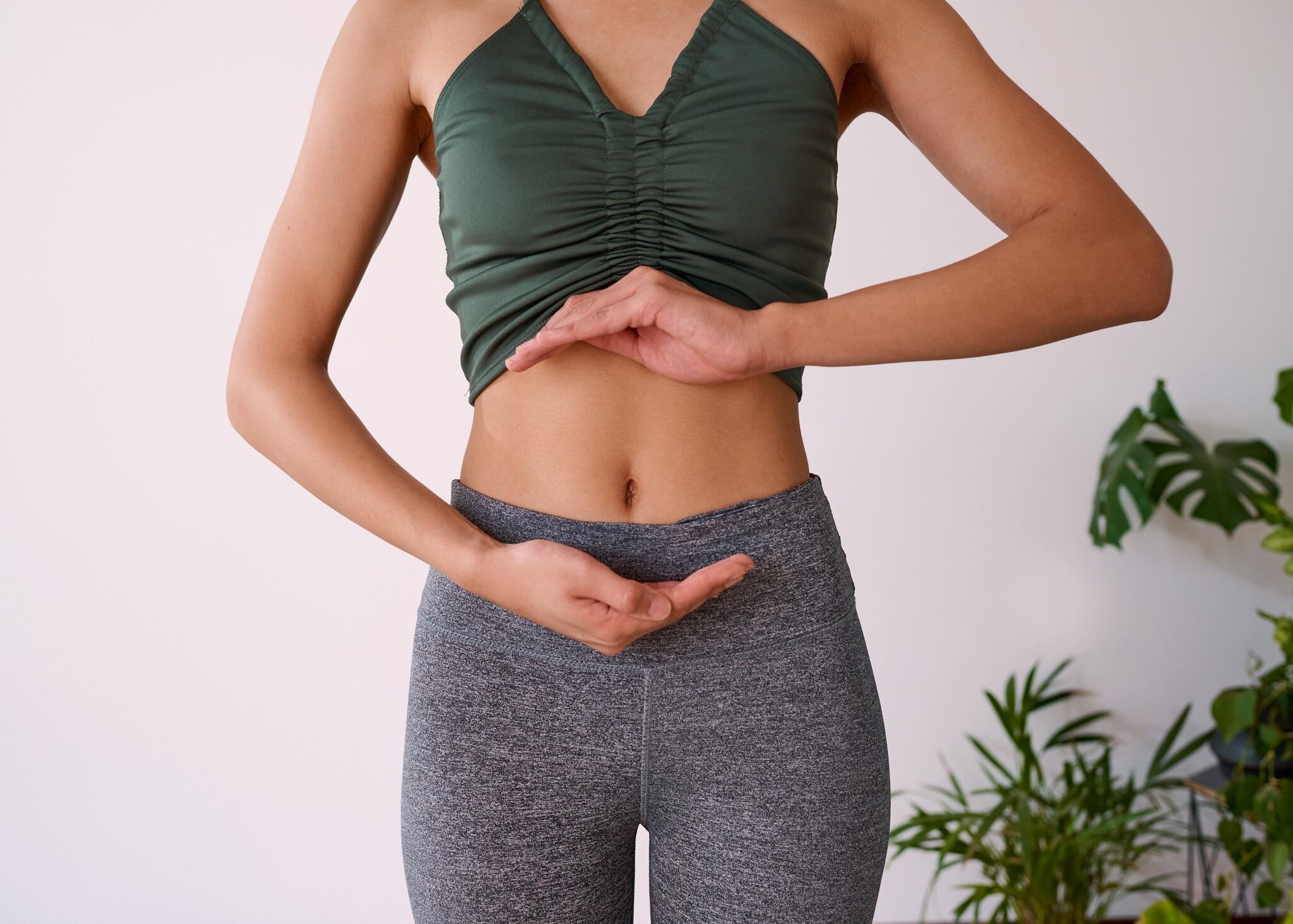 Close up of a young multi-ethnic woman's stomach cupped by her hands. High quality photo.