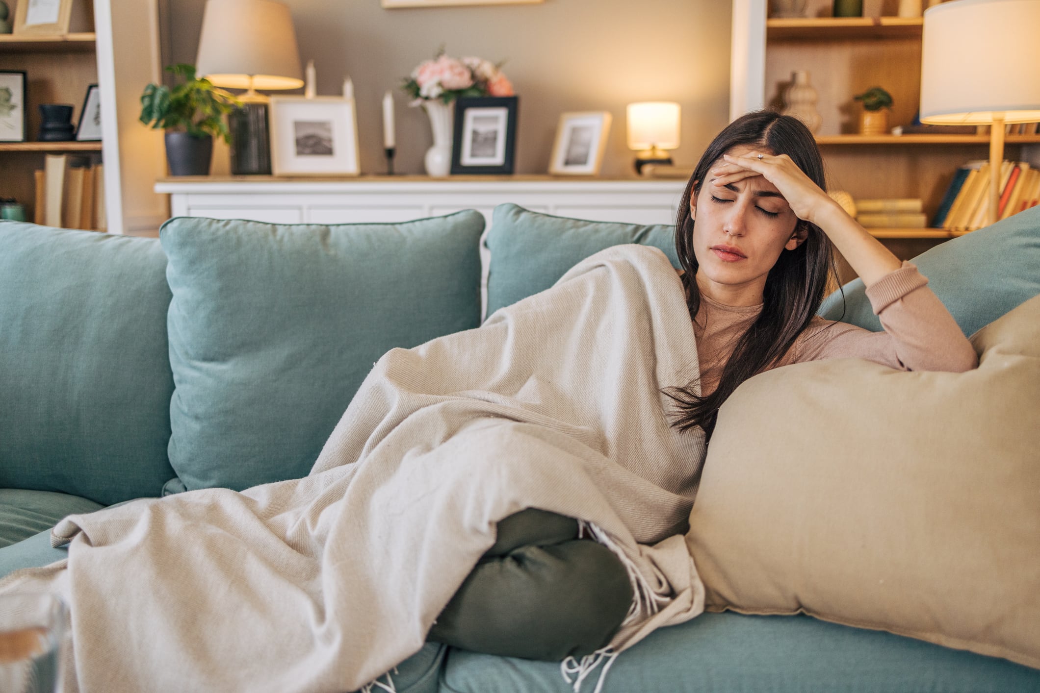 A young woman lying on the sofa in the living room, feeling sick.