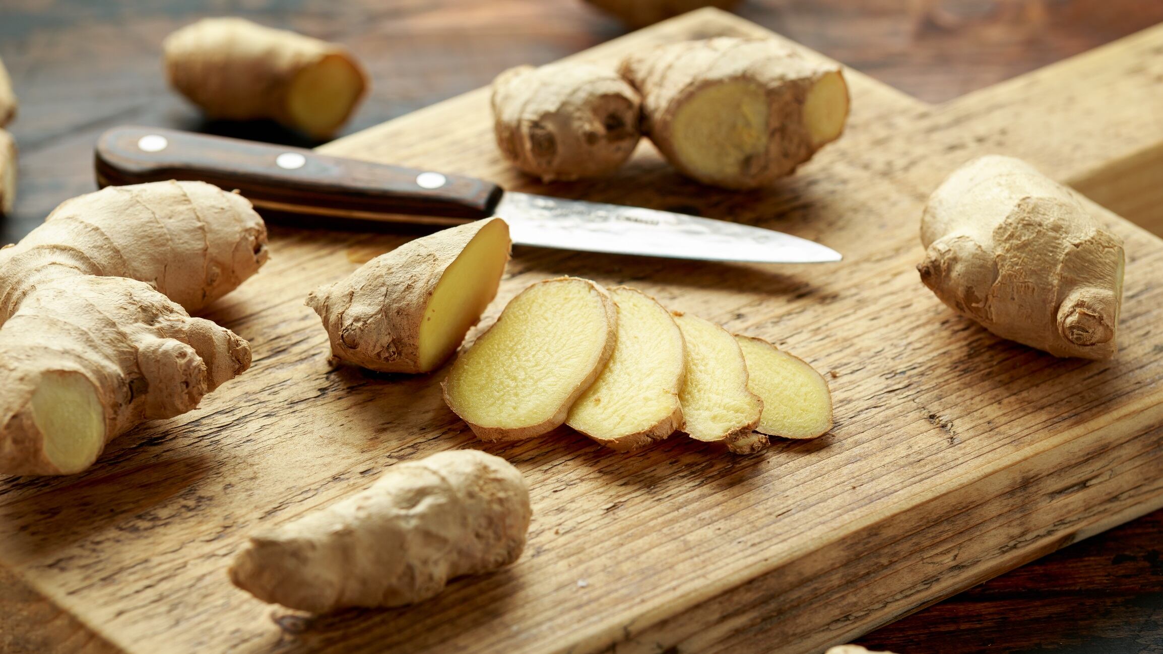 Fresh slice of Ginger on wooden chopping board. healthy food.
