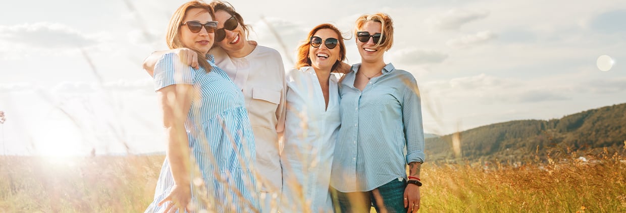 Portrait of four cheerful smiling and laughing women embracing
