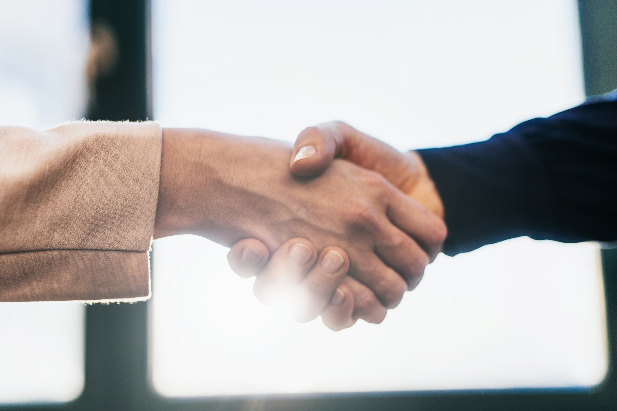 Two business women shaking hands in office.