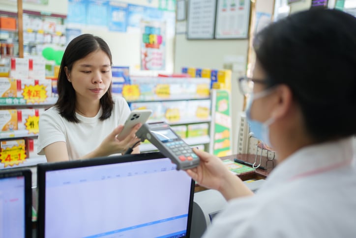 A woman paying for her items bought at a pharmacy using mobile phone app.