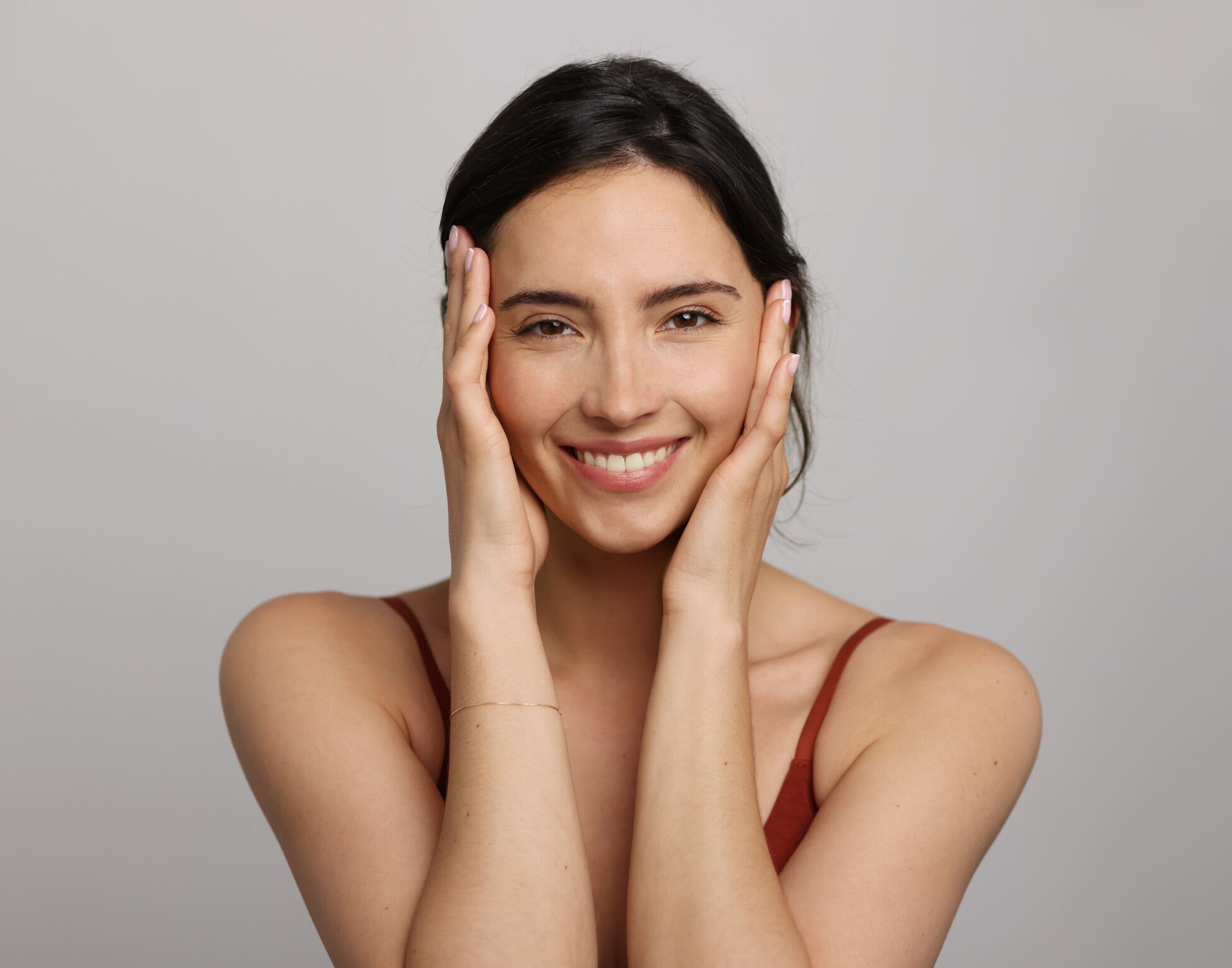 A brunette woman posing with her hand resting on her face