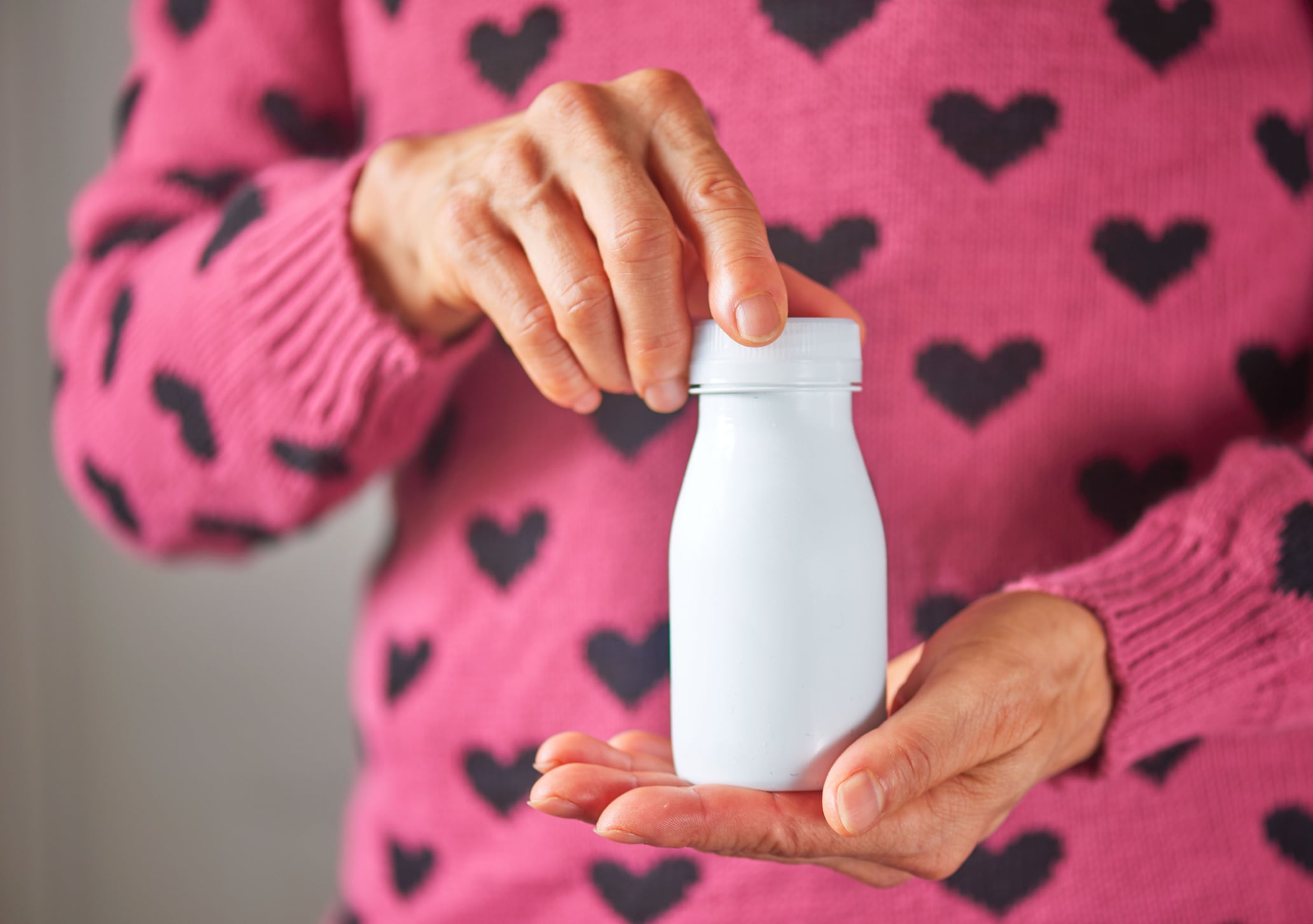 Holding a bottle of probiotic drink .