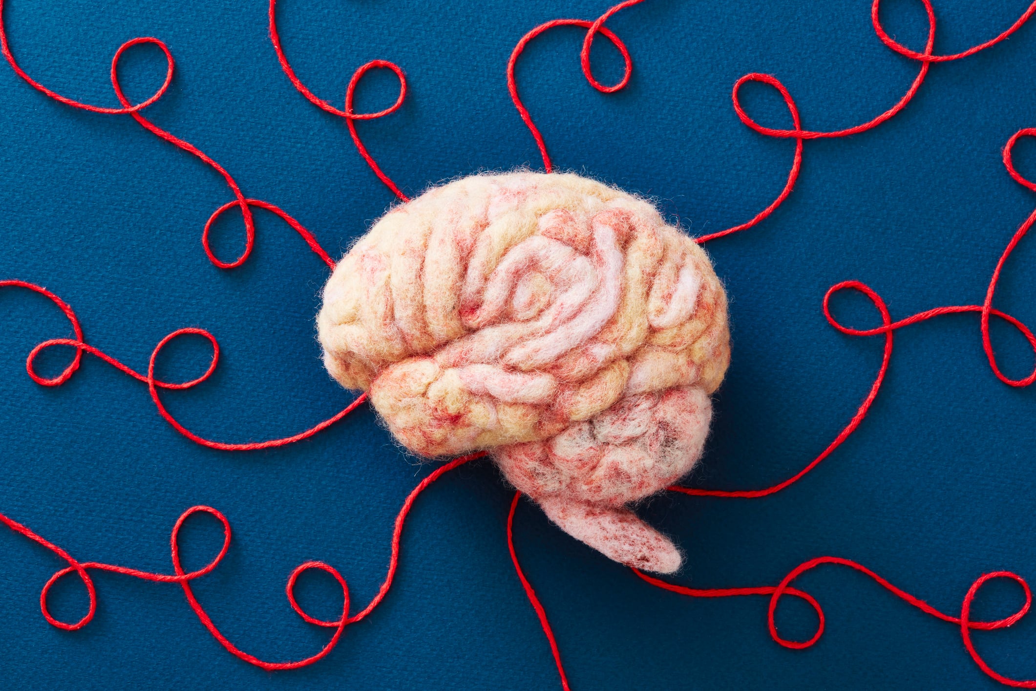 Human brain made of wool with string representing neural pathways