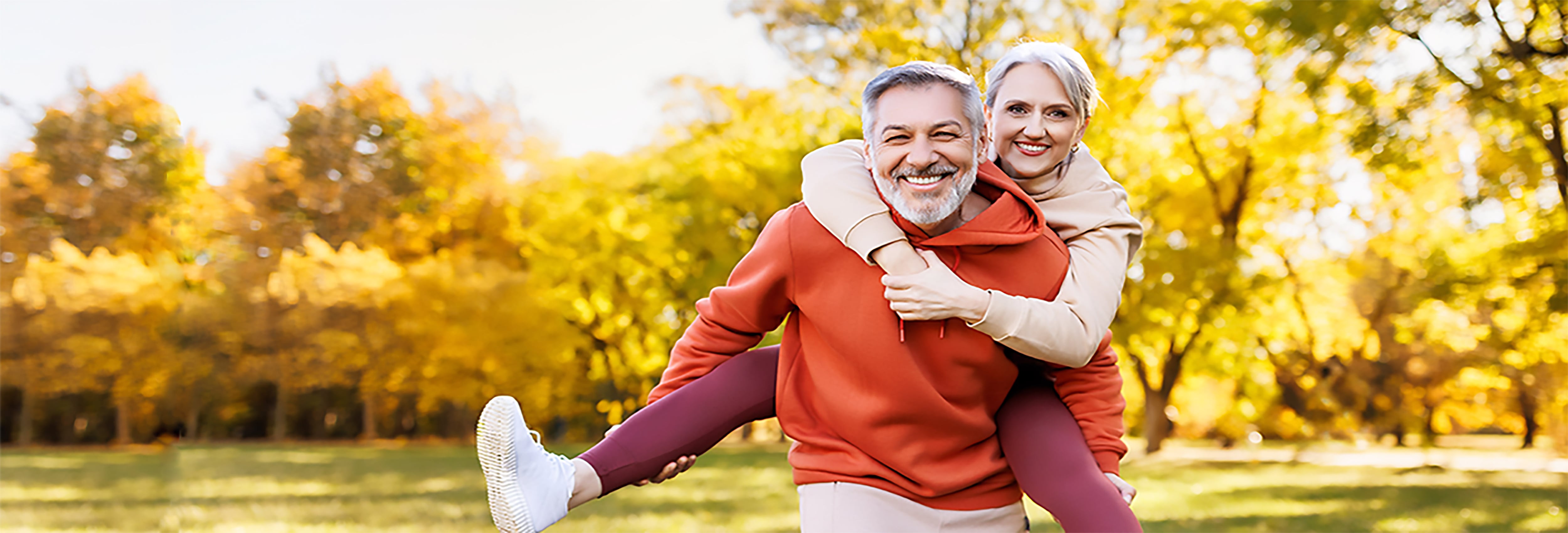 Couple piggyback during walk in the park