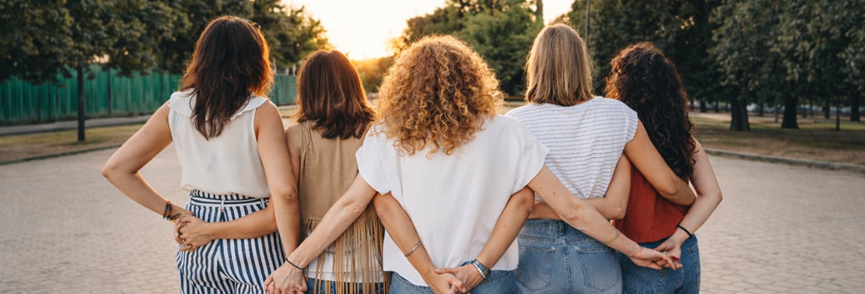 Women linking arms and looking at sunset