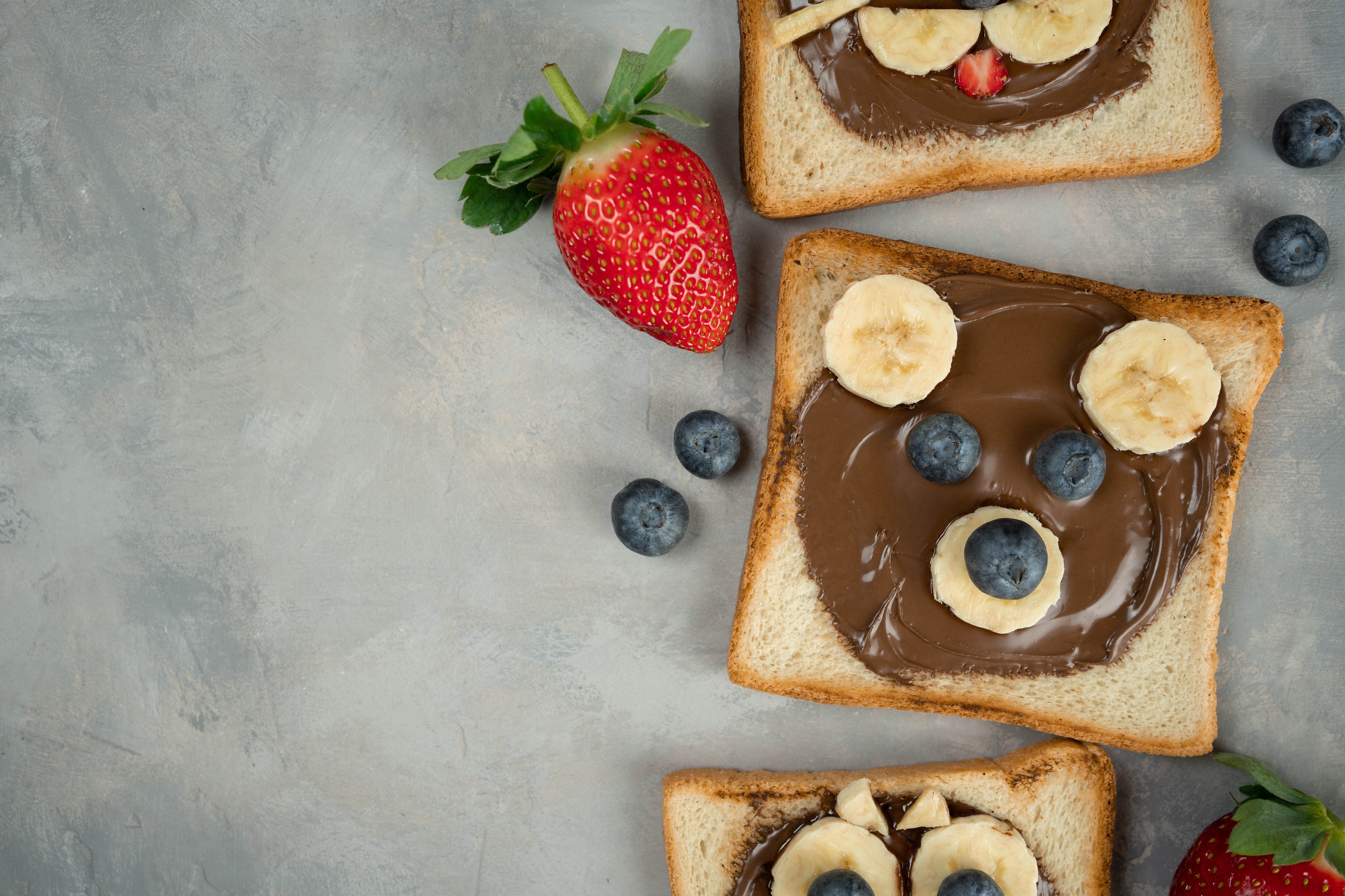 Kids breakfast or lunch or snack toast with chocolate hazelnut spread, banana and blueberry shaped as cute bear. Children's food menu