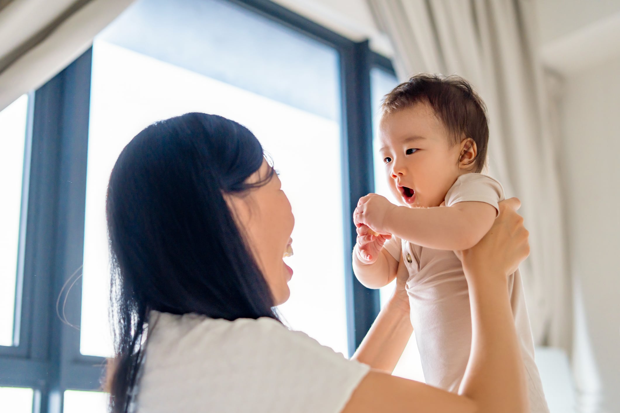 close up of young mother lifting baby girl at home