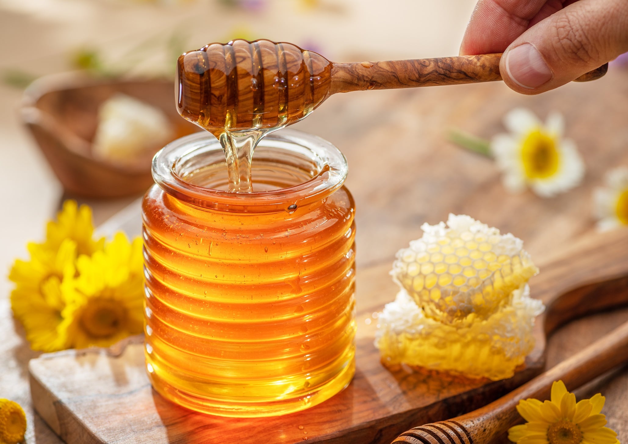 Natural organic honey in glass jar, honey dipper and honeycombs are near. Natural food background.
