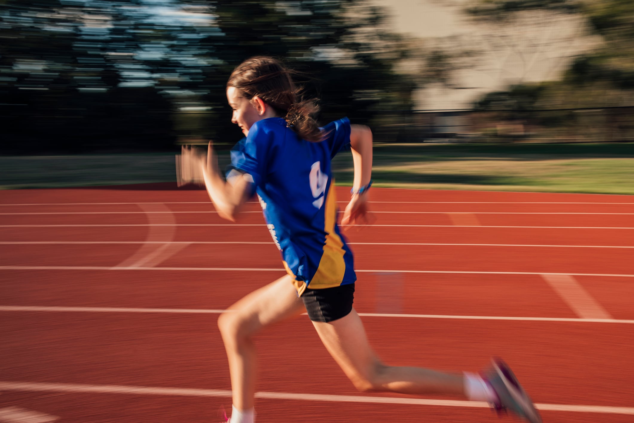 Little girl is doing speed training on the running track at athletics club.