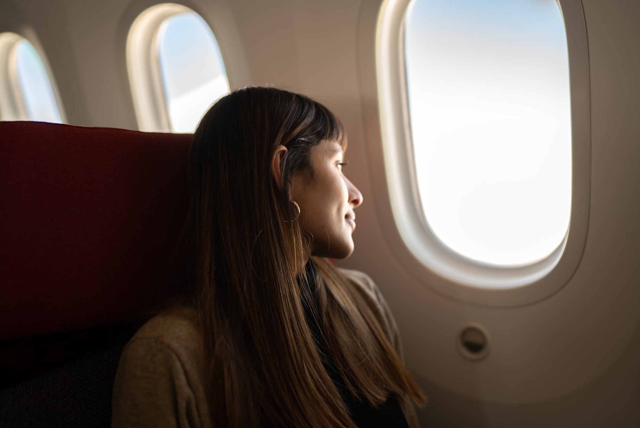Young woman traveling by plane looking out the window