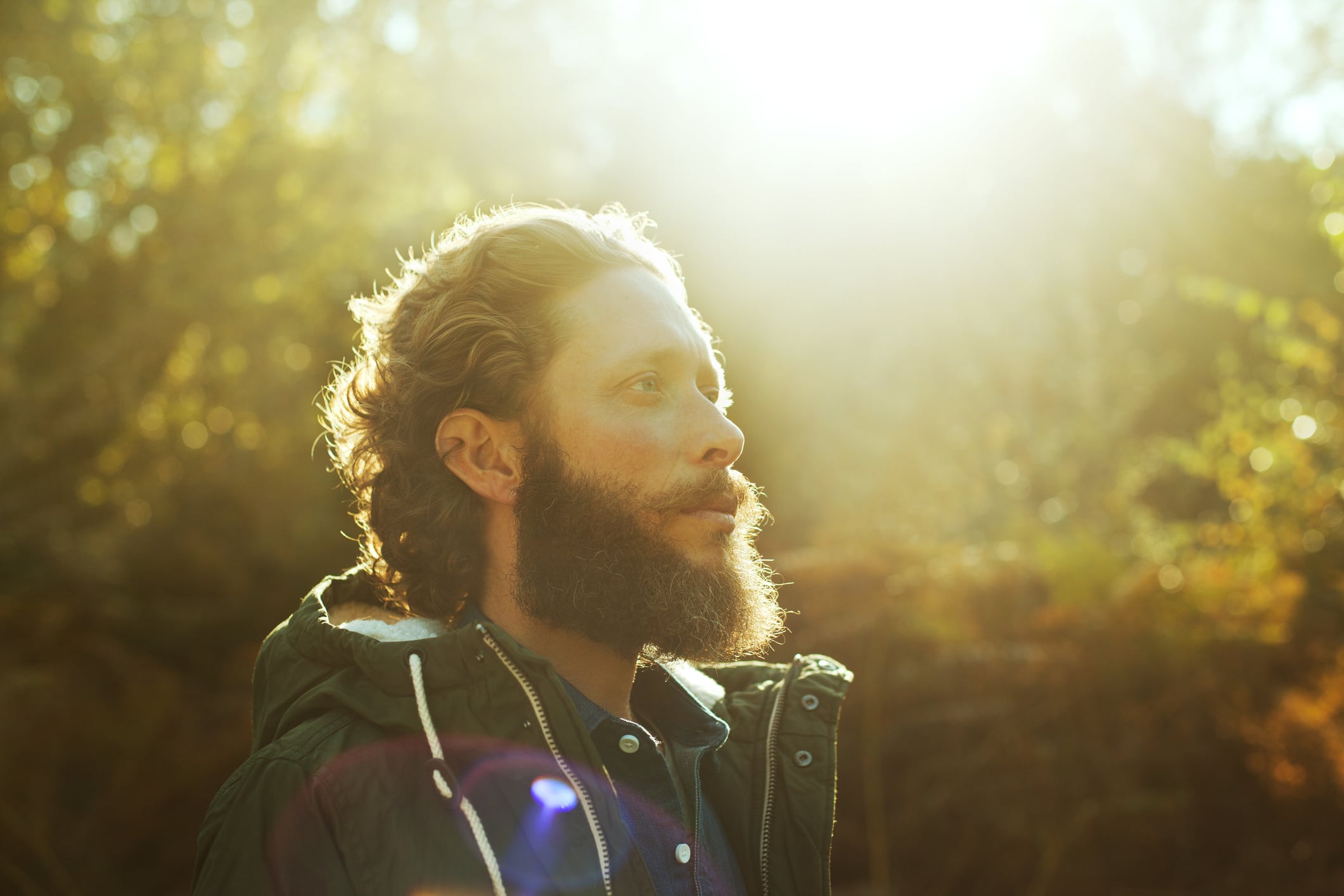 Man stands in sunlight forest, symbolizing the connection between nature and vitamin D