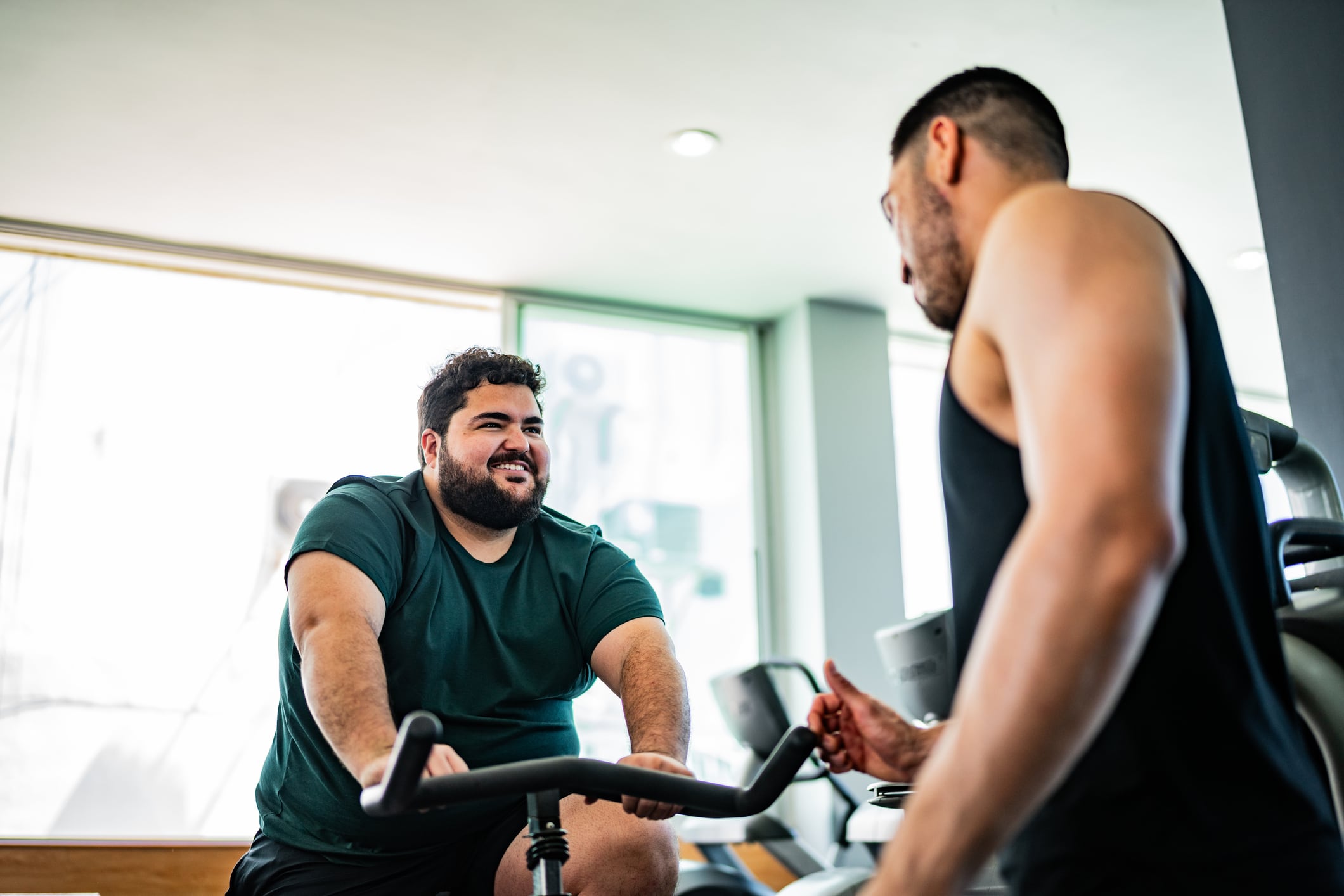 Man talking to instructor on exercise bike at gym