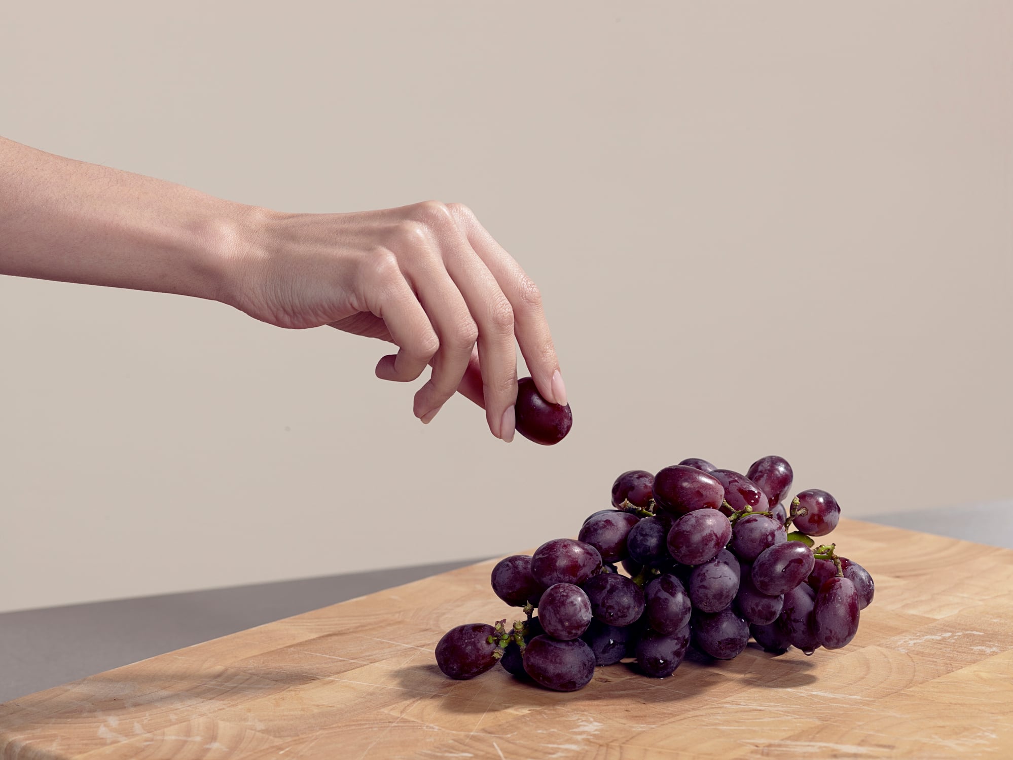 Woman taking a grape purple grape that could aid sports performance
