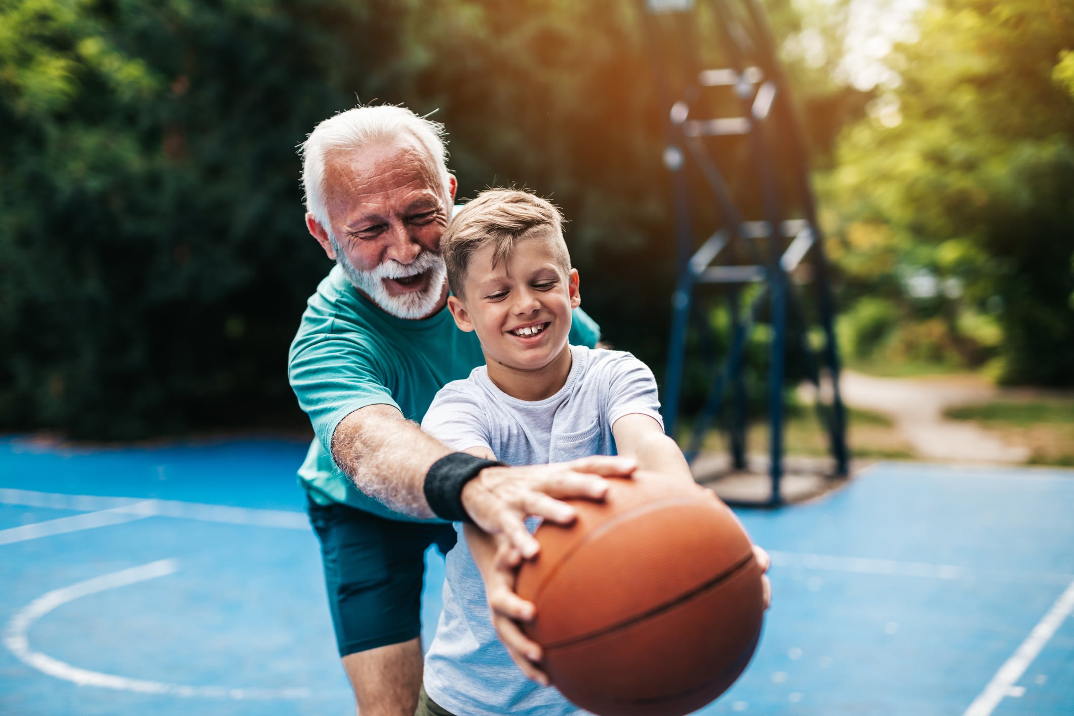 Grandfather and his grandson enjoying and playing together on basketball court.