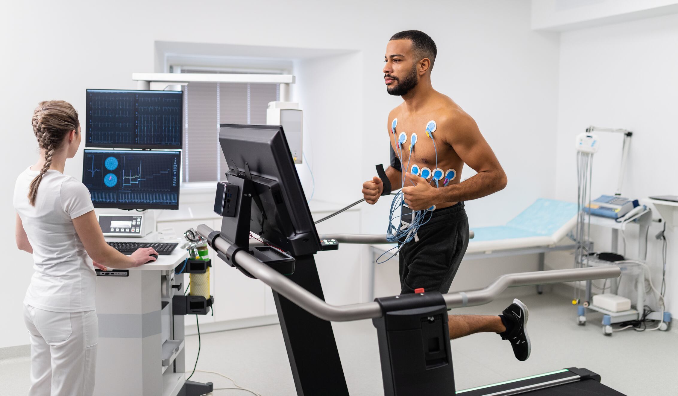 Athlete does a cardiac stress test in a medical study, monitored by the female doctor.